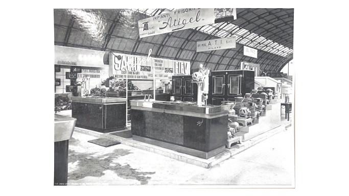 Vendita al dettaglio in un negozio con espositori e clienti, in un ambiente ampio e luminoso.