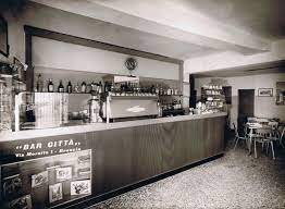 Vintage café interior featuring a counter, espresso machine, and tables.